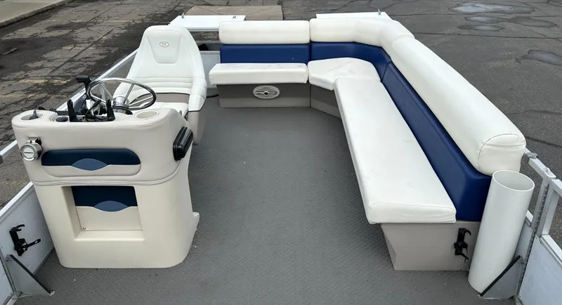 Slide: The Image of 1990 Crest III pontoon boat interior with white and blue seating and steering console. - 14
