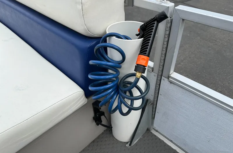Slide: The Image of Coiled blue hose in a Crest III 1990 boat, stored beside white and blue seating. - 15