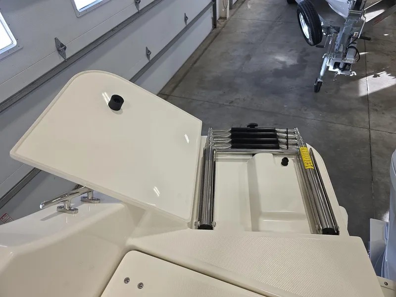 Slide: The Image of 2025 Boston Whaler 210 Vantage boat ladder and storage compartment in a garage setting. - 10