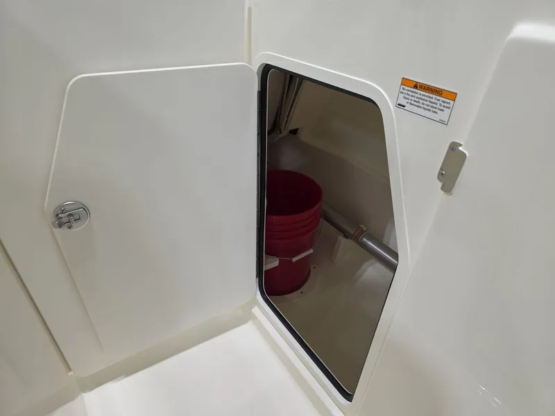 Slide: The Image of 2025 Boston Whaler 210 Vantage storage compartment with red bucket inside. - 16