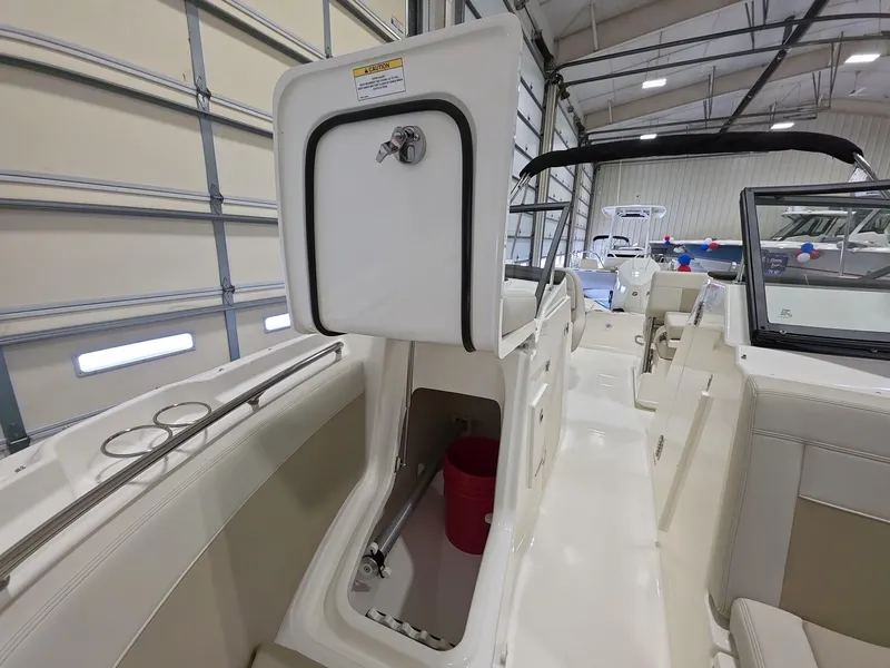 Slide: The Image of 2025 Boston Whaler 210 Vantage interior, showcasing storage compartment and seating in a boat garage. - 18
