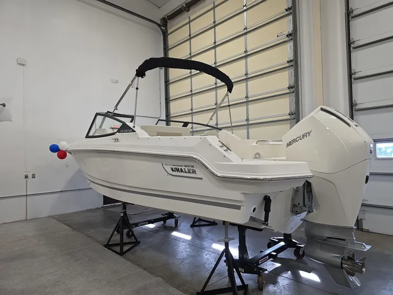 Slide: The Image of 2025 Boston Whaler 210 Vantage boat in a garage, featuring a Mercury engine. - 3