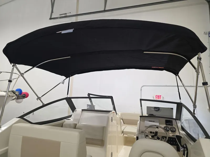 Slide: The Image of 2025 Boston Whaler 210 Vantage boat interior with black canopy and steering console. - 4