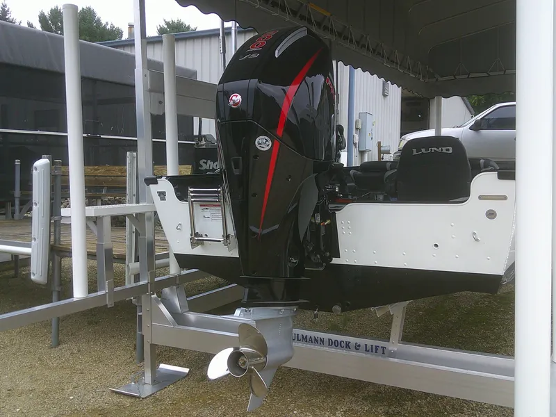 Slide: The Image of 2024 Lund 2075 Pro Guide boat on lift with powerful outboard motor. - 13