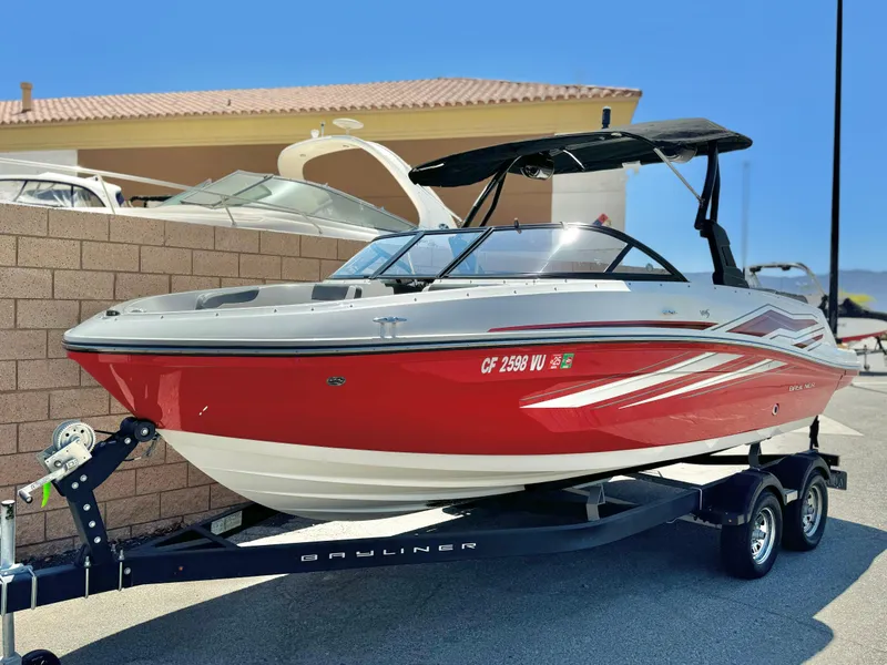 Slide: The Image of 2021 Bayliner VR5 Bowrider I/O, red and white, on trailer, parked outdoors. - 4