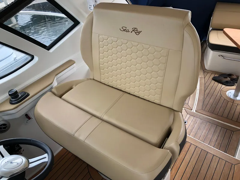 Slide: The Image of 2018 Sea Ray 350 Sundancer Coupe interior with beige leather seating and wood flooring. - 10