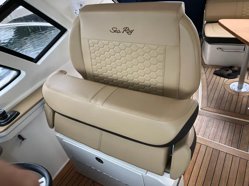 Slide: The Image of Captain's seat in 2018 Sea Ray 350 Sundancer Coupe, featuring beige upholstery and wood flooring. - 11
