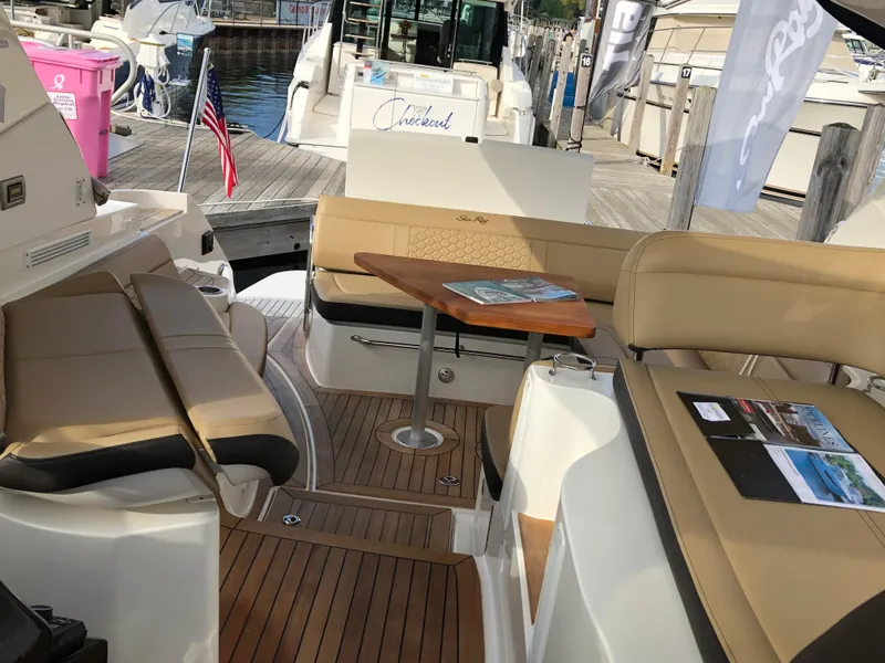 Slide: The Image of 2018 Sea Ray 350 Sundancer Coupe interior with seating and table, docked at marina. - 12