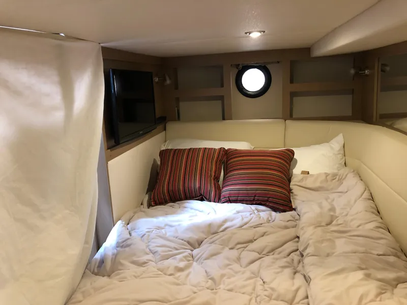 Slide: The Image of Cozy cabin interior of 2018 Sea Ray 350 Sundancer Coupe with bed and striped pillows. - 18