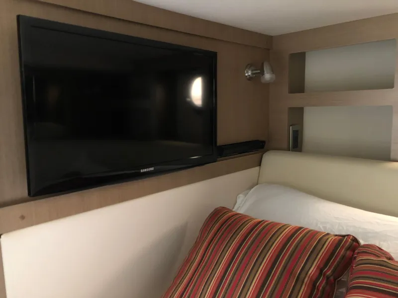 Slide: The Image of Interior of 2018 Sea Ray 350 Sundancer Coupe with wall-mounted TV and striped pillows. - 19