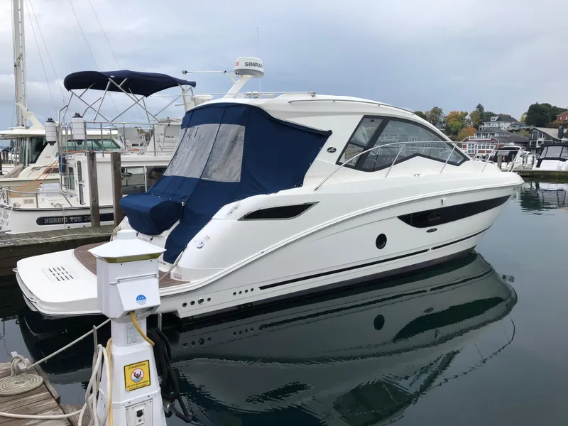 Slide: The Image of 2018 Sea Ray 350 Sundancer Coupe docked at marina, featuring sleek design and blue canopy. - 28