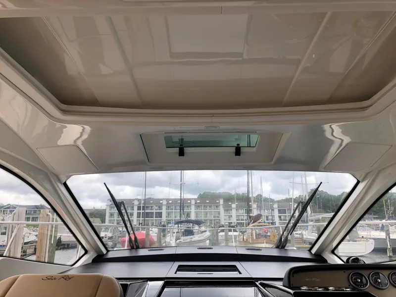 Slide: The Image of Interior view of 2018 Sea Ray 350 Sundancer Coupe at marina, showcasing dashboard and windshield. - 5