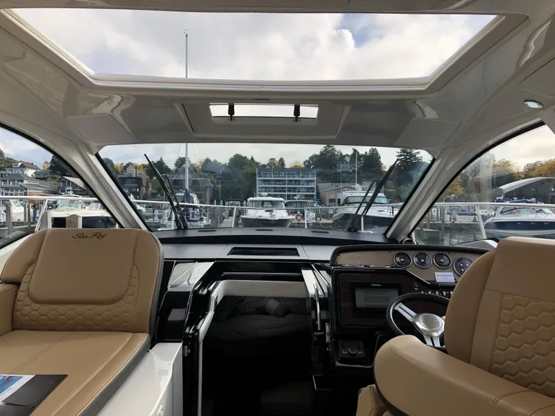 Slide: The Image of Interior view of 2018 Sea Ray 350 Sundancer Coupe at marina, featuring helm and seating. - 6
