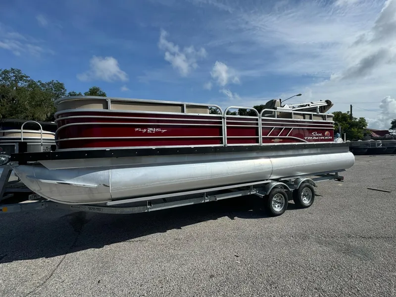 Slide: The Image of 2023 Sun Tracker Party Barge 24 DLX pontoon boat on trailer, parked outdoors. - 3
