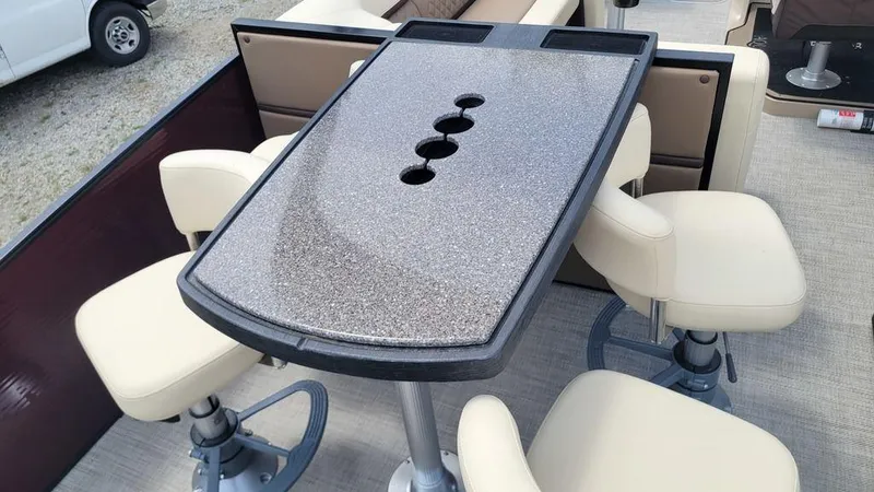 Slide: The Image of 2023 AquaPatio 275 CBE iMPACT boat interior with table and swivel chairs. - 10