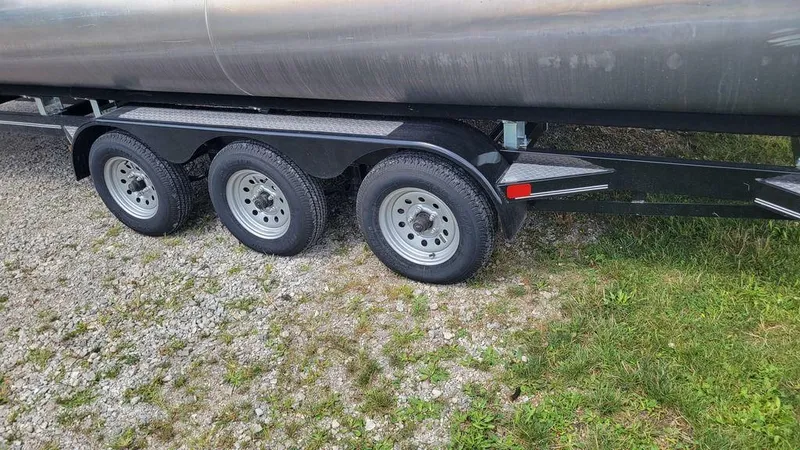 Slide: The Image of 2023 AquaPatio 275 CBE iMPACT trailer with triple axle on gravel and grass. - 12