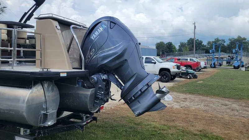 Slide: The Image of 2023 AquaPatio 275 CBE iMPACT boat with Yamaha outboard motor, parked on grass. - 13