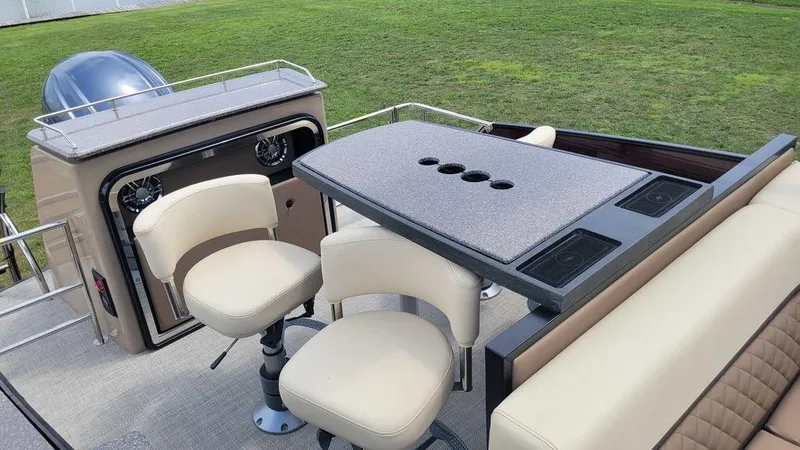 Slide: The Image of 2023 AquaPatio 275 CBE iMPACT boat interior with seating and table setup. - 3