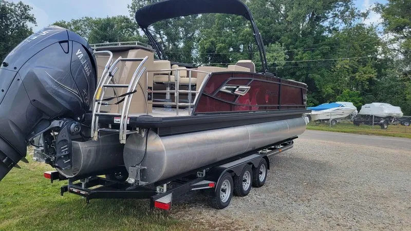 Slide: The Image of 2023 AquaPatio 275 CBE iMPACT pontoon boat on trailer, parked outdoors. - 9