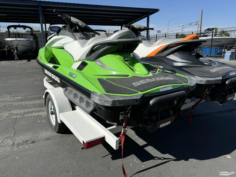 Slide: The Image of 2014 Sea-Doo GTI 130 SE/GTI 155 SE jet skis on trailer, green and black design. - 2