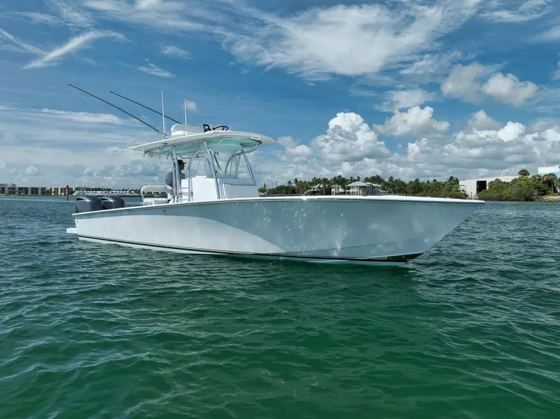 Slide: The Image of 1995 Jupiter 31 Center Console boat on calm water under a partly cloudy sky. - 33