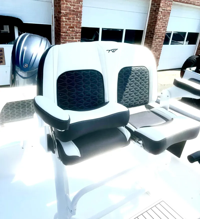 Slide: The Image of Tidewater 220LXF 2025 boat seats with black and white upholstery, parked near brick garage. - 3