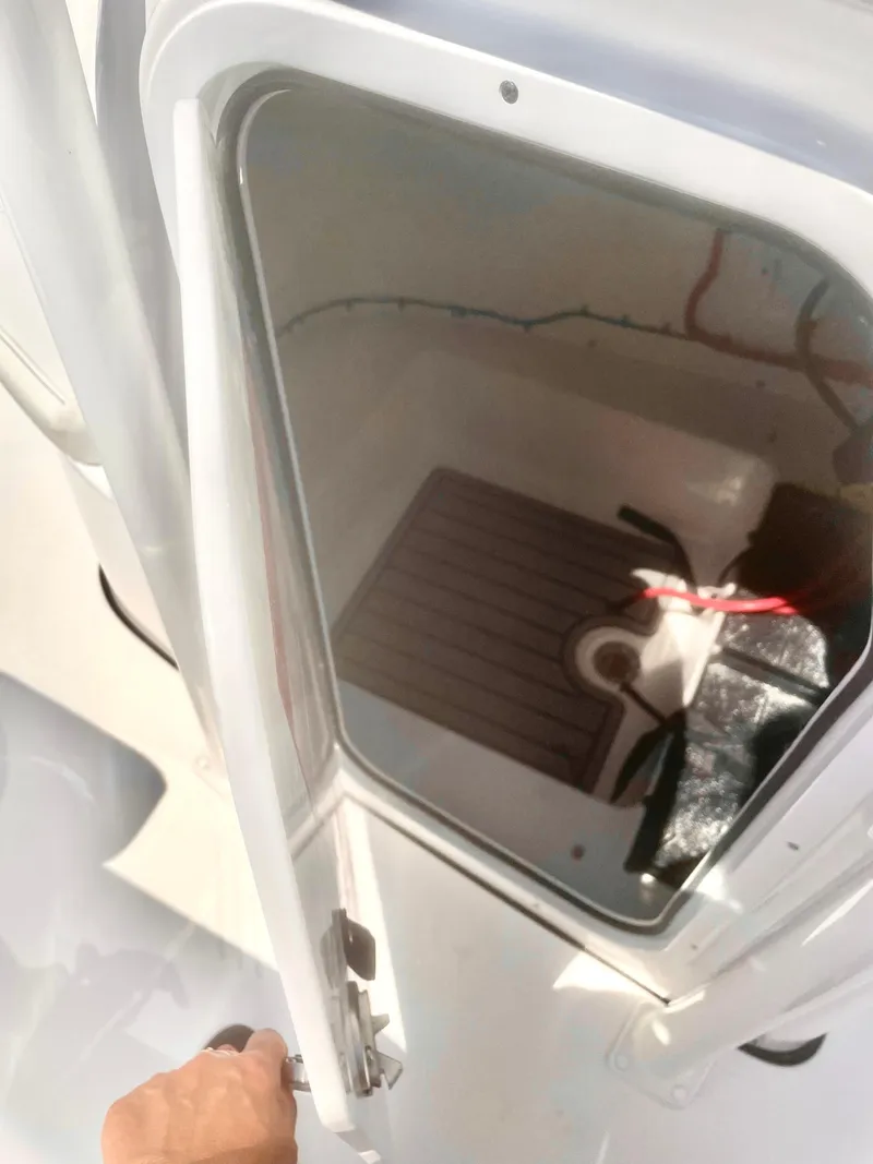 Slide: The Image of 2025 Tidewater 220LXF boat storage compartment with open door, showing interior details. - 7