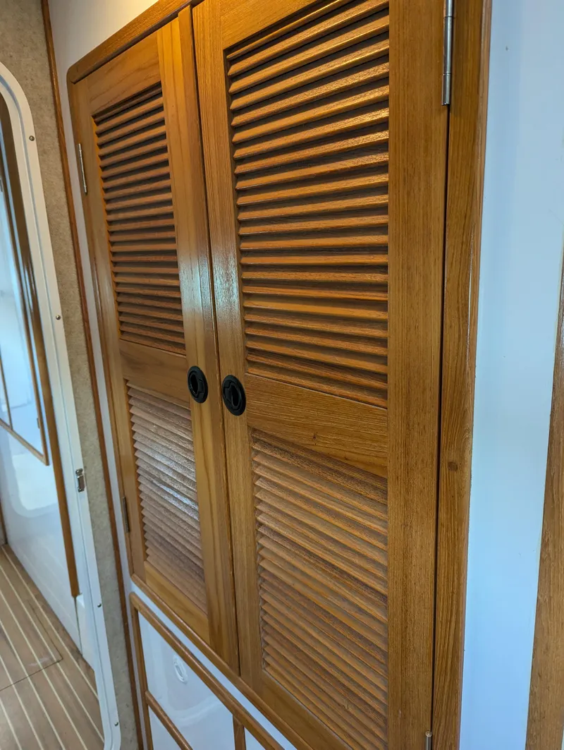 Slide: The Image of Wooden louvered cabinet doors inside a 2000 Manta 42 boat interior. - 16