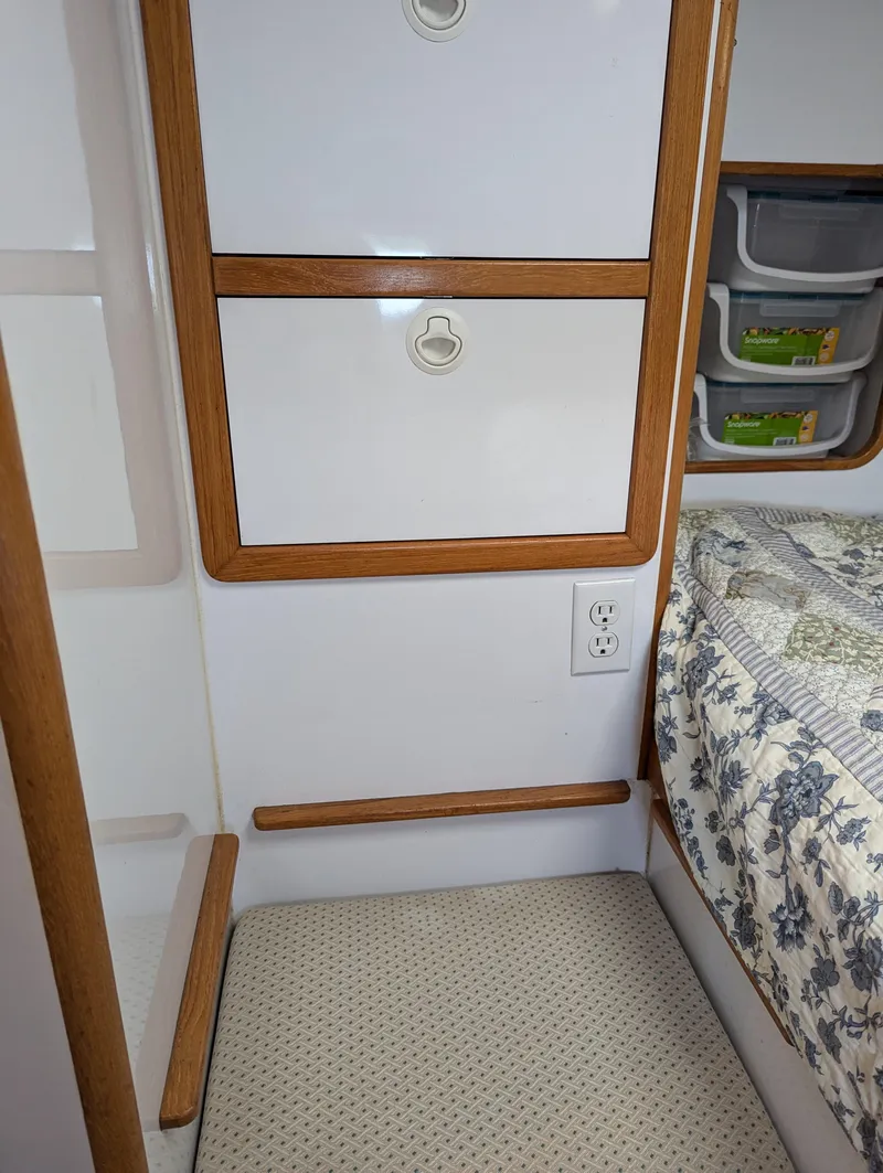 Slide: The Image of Interior of a 2000 Manta 42 boat with storage drawers and a patterned bedspread. - 17