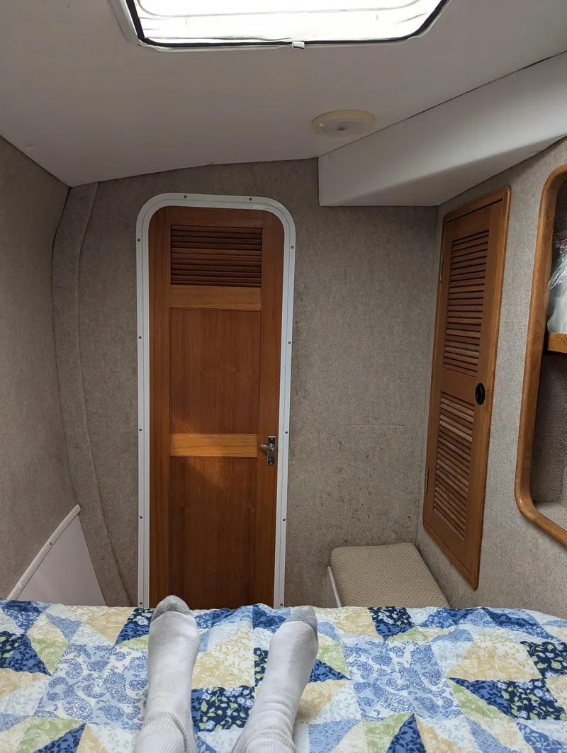 Slide: The Image of Interior cabin view of a 2000 Manta 42 sailboat, featuring wooden doors and cozy bedding. - 26