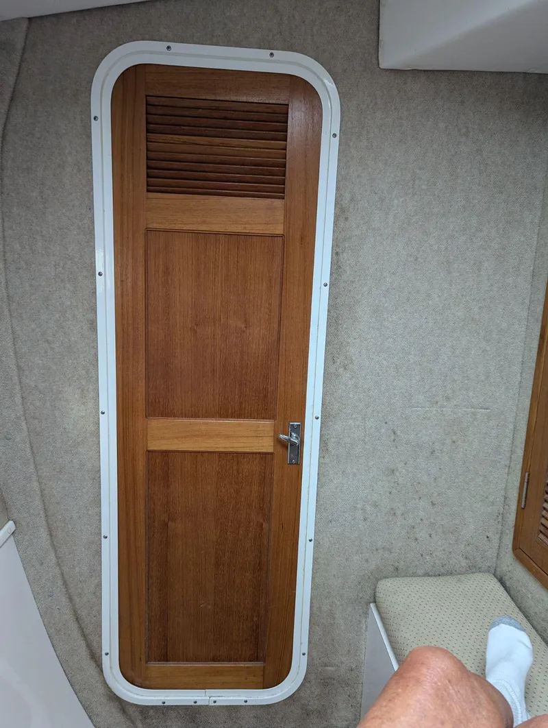 Slide: The Image of Wooden door inside a 2000 Manta 42 boat cabin, featuring a vented panel. - 30