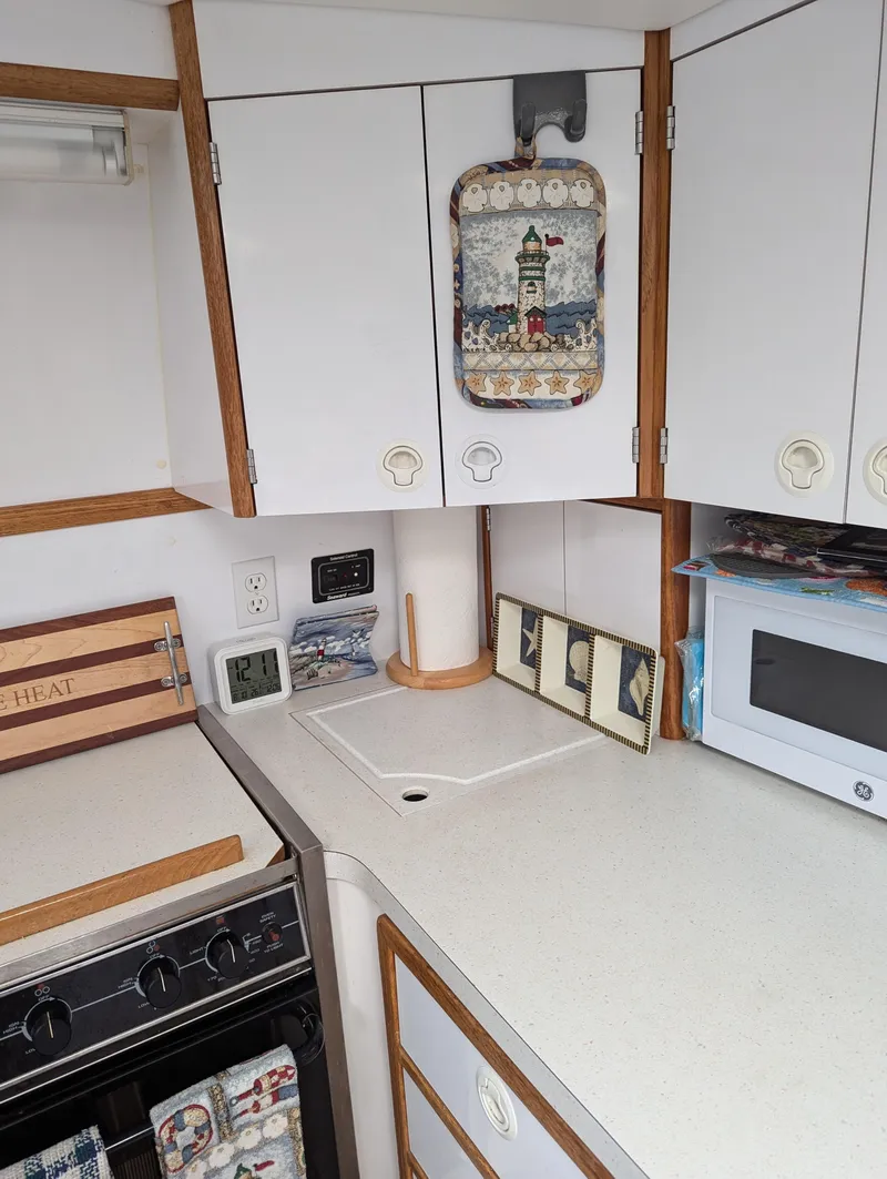 Slide: The Image of Compact kitchen area in a 2000 Manta 42 boat, featuring white cabinets and a microwave. - 39