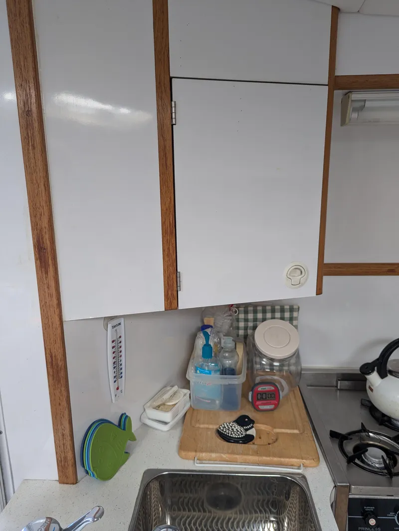 Slide: The Image of Compact kitchen area in a 2000 Manta 42 boat, featuring white cabinets and a stainless steel sink. - 41