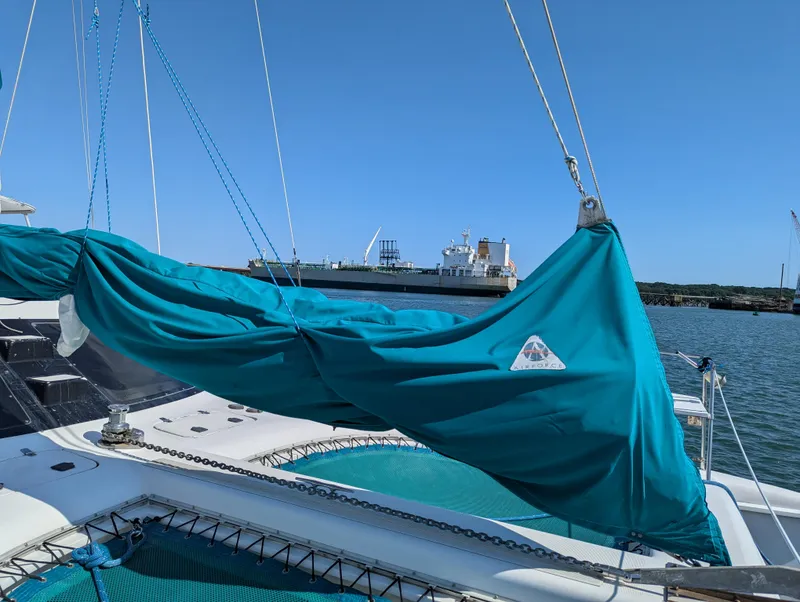 Slide: The Image of Manta 42 sailboat from 2000 with turquoise sail cover, docked near a large ship. - 9
