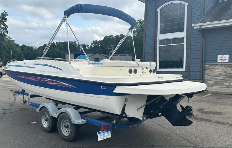 Slide: The Image of 2006 Bayliner 217 boat on trailer, parked near a building. - 2