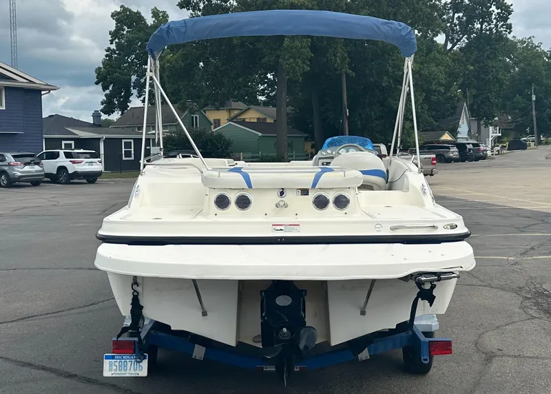 Slide: The Image of 2006 Bayliner 217 boat with blue canopy on trailer, parked in residential area. - 4