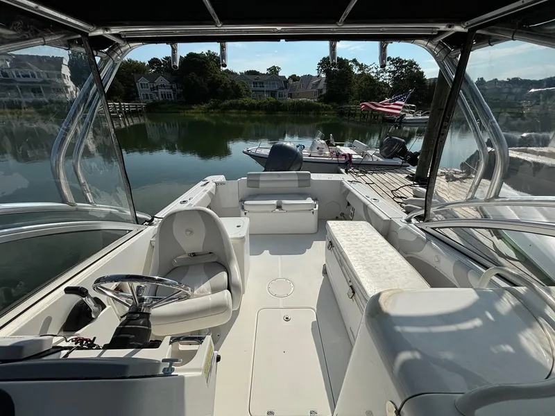 Slide: The Image of 2011 Edgewater 245 CX boat interior, docked by a serene waterfront with lush greenery. - 6