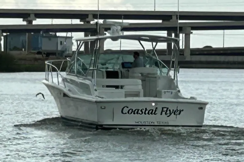 Slide: The Image of 1996 Hatteras 39 Sport Express boat named "Coastal Flyer" on water near a bridge. - 3