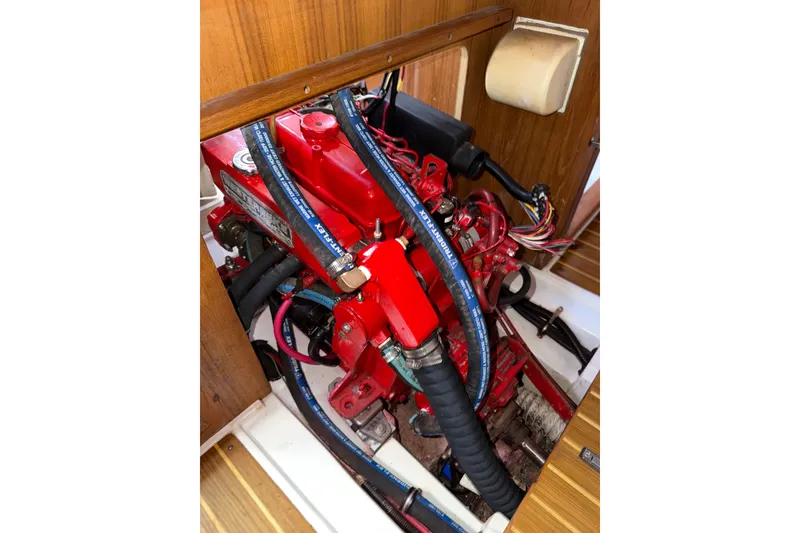 Slide: The Image of Engine compartment of a 1998 Catalina 380 sailboat, featuring a red engine and hoses. - 15