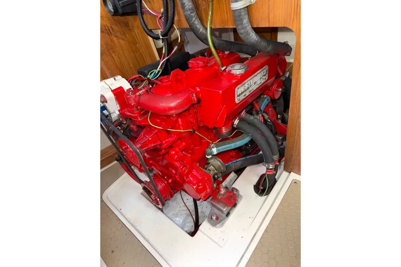 Slide: The Image of Red marine engine in a 1998 Catalina 380 sailboat, featuring hoses and wiring. - 14