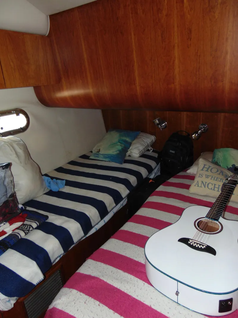 Slide: The Image of Cozy cabin interior of 2000 Tiara Yachts 5000 Express with striped bedding and guitar. - 25
