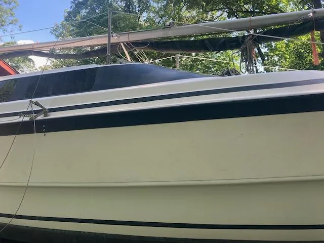 Slide: The Image of 1997 MacGregor 26 X sailboat with mast, docked under trees. - 3