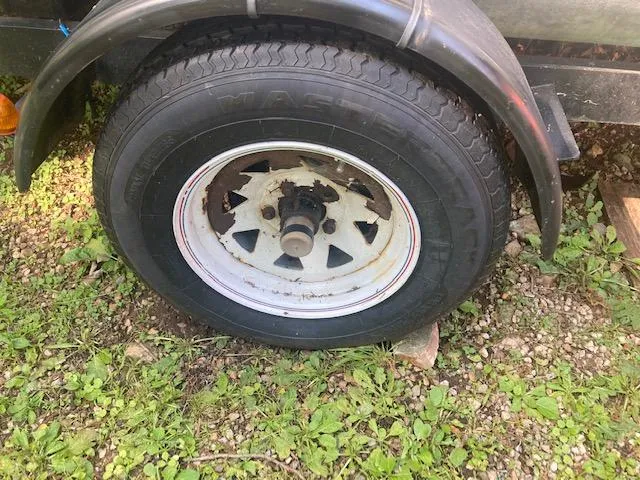 Slide: The Image of Trailer wheel of a 1997 MacGregor 26 X on grassy ground. - 5