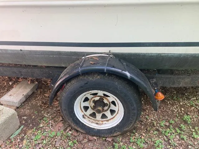 Slide: The Image of Trailer wheel of a 1997 MacGregor 26 X boat, with visible wear and rust. - 6