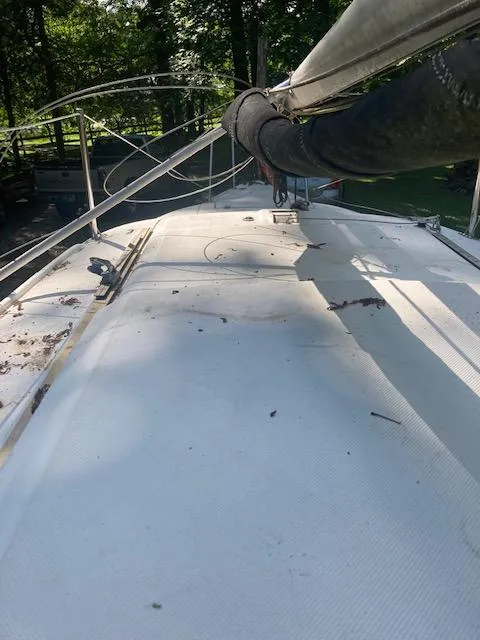 Slide: The Image of 1997 MacGregor 26 X sailboat deck with mast, surrounded by trees. - 8