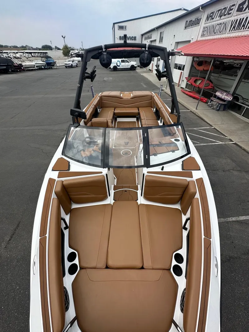 Slide: The Image of 2023 Axis T250 boat with brown seating, docked near a dealership. - 11