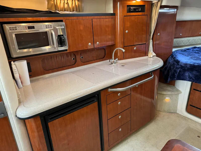 Slide: The Image of 2007 Sea Ray 340 Sundancer interior with kitchenette, featuring wood cabinets and modern appliances. - 17