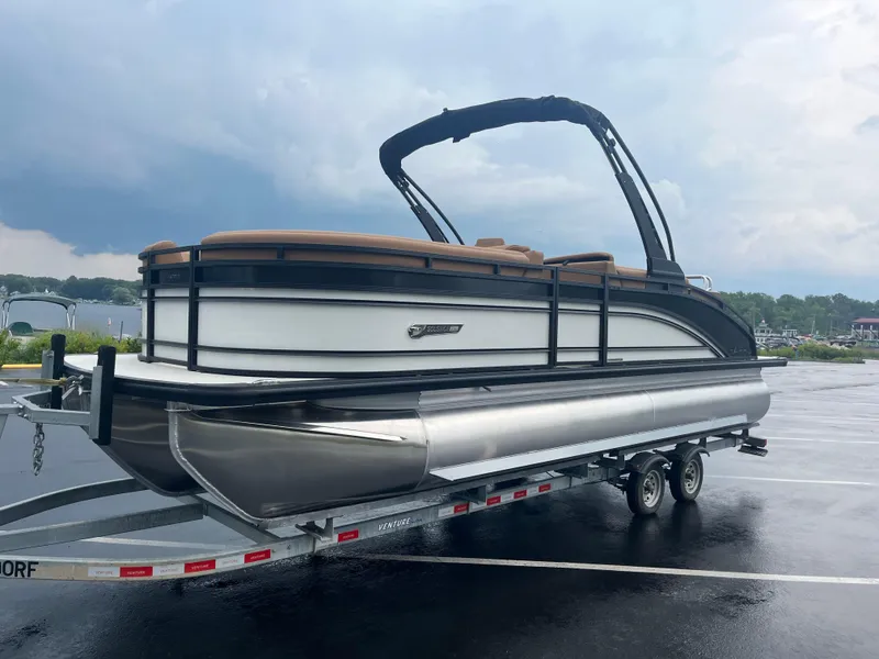 Slide: The Image of 2025 Harris Solstice 230 pontoon boat on trailer, parked on wet pavement. - 10
