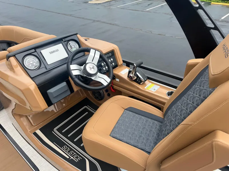 Slide: The Image of 2025 Harris Solstice 230 boat interior with tan and black seating, modern dashboard, and steering wheel. - 6