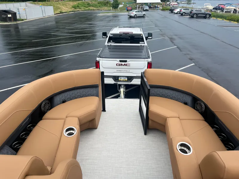 Slide: The Image of 2025 Harris Solstice 230 pontoon boat interior with tan seating, parked in a lot. - 7
